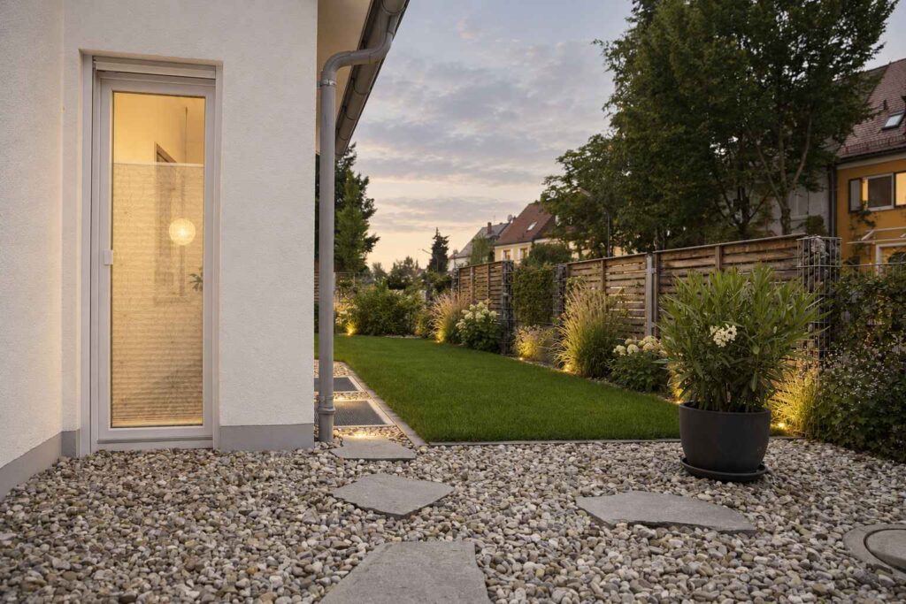 Seitlicher Gartenbereich mit Rasen, Kies und Trittplatten am Haus in München-Laim