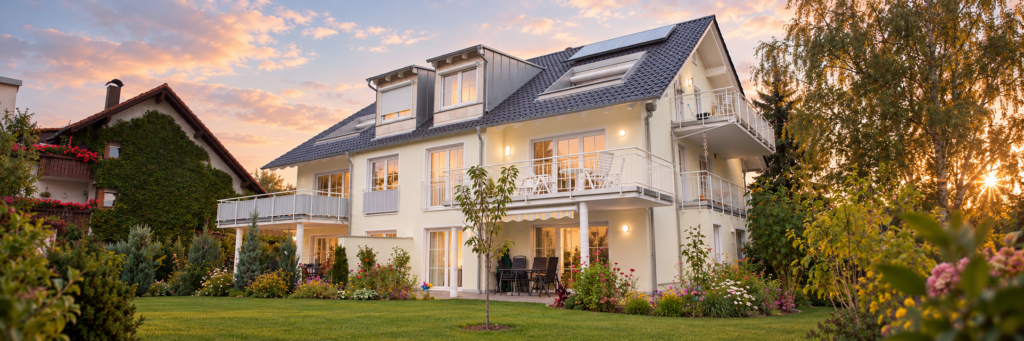 Doppelhaus in Puchheim mit heller Fassade, weißen Balkonen, Dachgauben und Garten