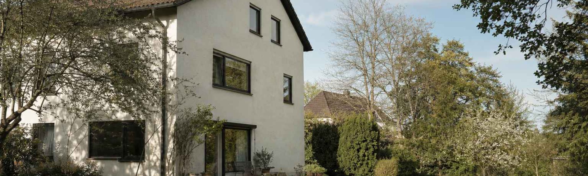 Wohnhaus mit Garten und großen Bäumen